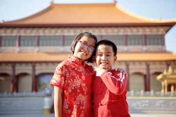 asian girl and boy wearing red chinese suit happiness against china temple background