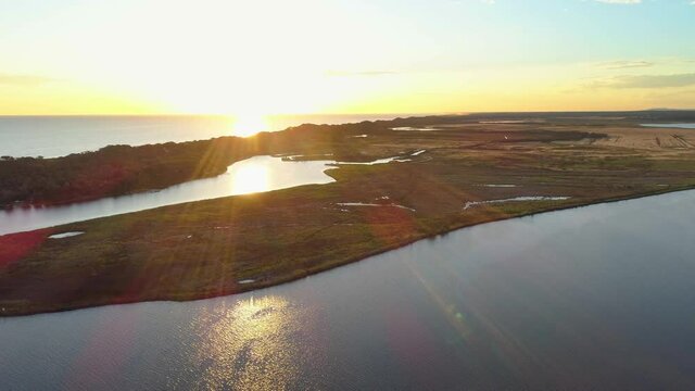 Forward flight over water and coastline towards the sun at sunset in Australia