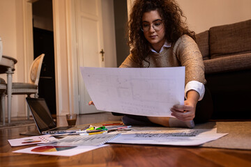 Young woman sitting on floor working at home in her living room.