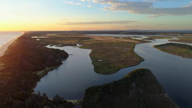 Slow aerial rise high above scenic ocean coastline and Snowy River at sunset. Marlo, Australia