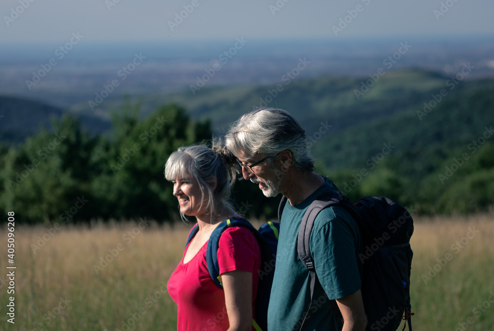 Wall mural active senior couple with backpacks hiking in nature .