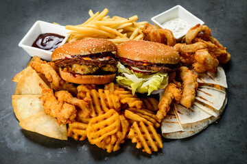Combined set of fast food. Juicy delicious hamburger, French fries, chicken legs and sauce on a black background. Fast food restaurant. Food delivery. large set of fast food burgers fries and snacks