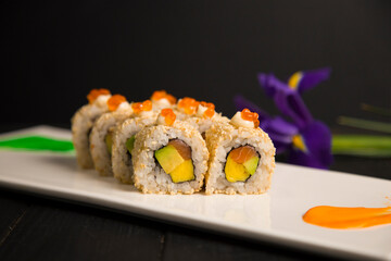 Close up of sushi roll with salmon, avocado, egg omelette wrapped, served with red caviar on top....