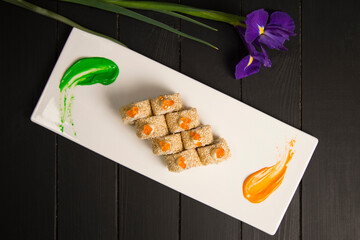 Top view of Japanese sushi roll served with red caviar on top. green and orange painting brush...