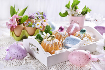 Obraz na płótnie Canvas Easter mini ring cakes and floral decoration on festive table