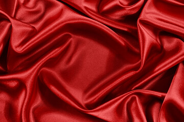 Red silk satin background. Shiny fabric with wavy soft pleats. Beautiful fabric background with...