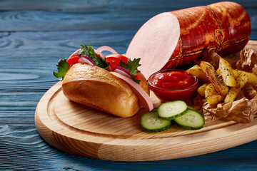 Mortadella with vegetables and herbs on a wooden plate on a wooden table.