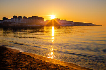 Sun rays at sunset over the city on the sea