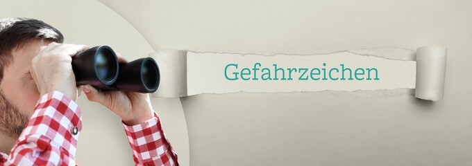 Gefahrzeichen. Mann (Anwalt) bei Beobachtung mit Fernglas. Fokus auf Wort/Text in einem Papier Riss.