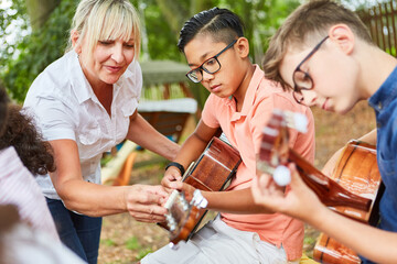 Teacher helps children in guitar lessons