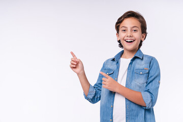 Amazed young male kid pointing at copy space isolated over white background