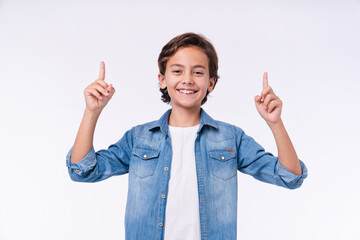 Happy small male kid in casual clothes pointing at copy space isolated over white background - Powered by Adobe
