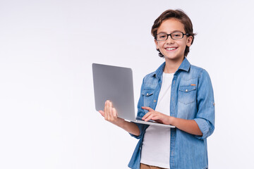 Smart little boy with laptop in casual clothes isolated over white background © InsideCreativeHouse