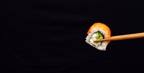 Banner with one sushi roll on black background with large copy space © Татьяна Качайло