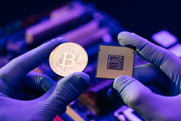 Closeup of man hands in gloves hold gold Bitcoin and cpu on motherboard background. Person shows...