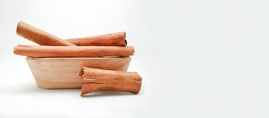 Cinnamon  stick (Cinnamomum zeylanicum or Cinnamomum verum) in wooden bowl on white background with copy space