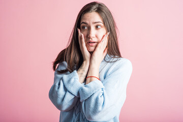 Scared brunette girl in studio on pink background