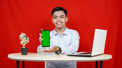 Young asian business man pointing handphone green screen isolated red background