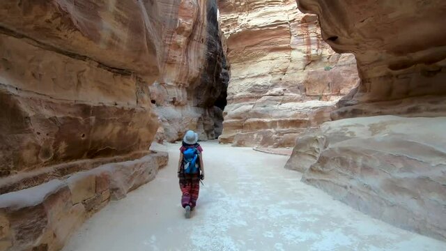 Tourist woman walking through the canyon of al-Siq in the Unesco heritage site of Petra, Jordan