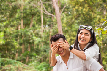 Asian couple love having fun. man and woman wearing casual clothing feeling happiness in park man closing eyes woman with attractive smile with hands