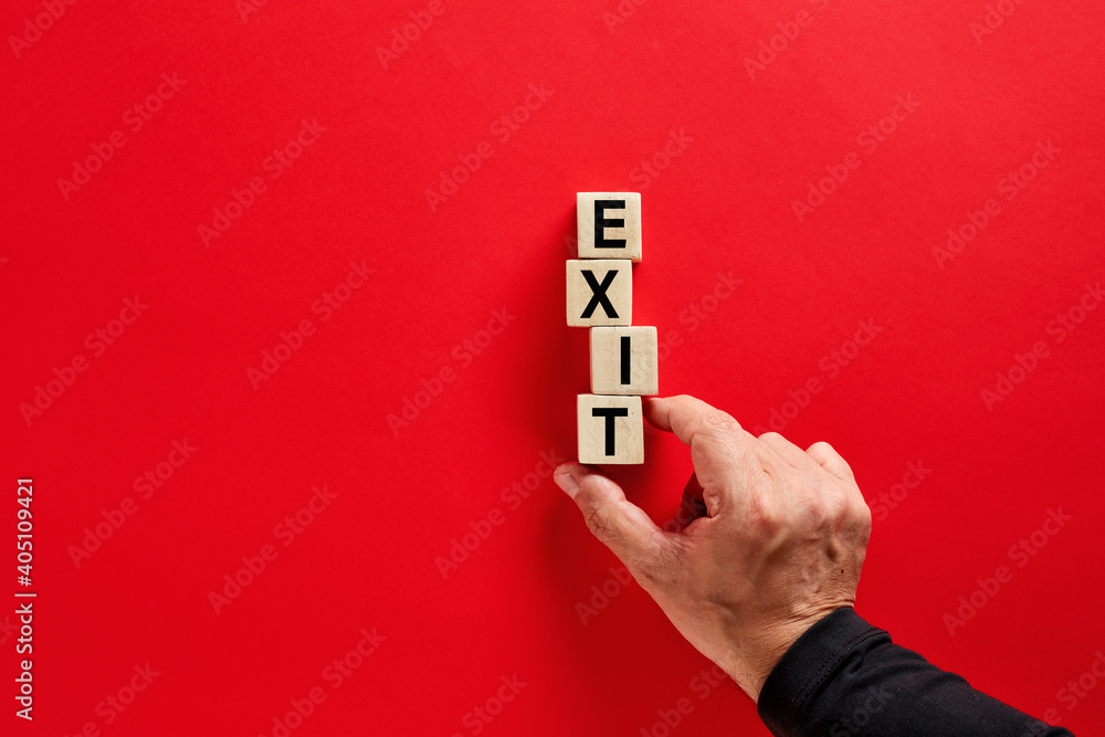 Poster male hand arranging the wooden blocks with the word exit on red background with copy space. decision