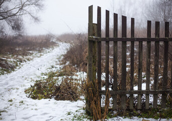 Fototapeta premium foggy winter day.snowy path to the fog.old fence.rural landscape