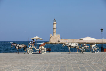 Two carriages in front of the Venetian lighthouse of Chania in Crete