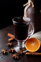 Hot autumn grog in a glass with honey and spices, ingredients around, laying on a wooden background