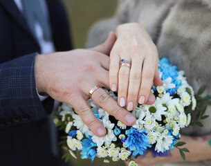 the groom and the bride hold hands on the background of the wedding bouquet