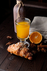 Hot berry tea and fresh crispy croissant on a wooden table with cinnamon and anise around, close up advertisement photo