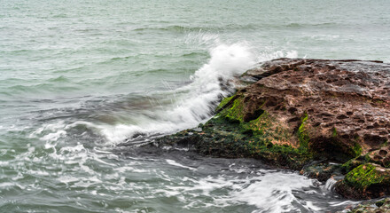 Wave splashing at the rocks, freshness on beach