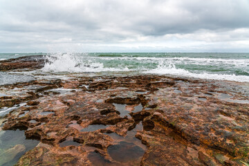 Wave splashing at the rocks, freshness on beach