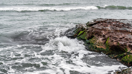 Wave splashing at the rocks, freshness on beach