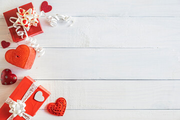 Red gift boxes and small heart decorations on white wooden background, top view, Valentines concept