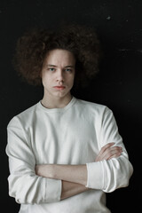 Portrait of young man in white with voluminous curly hair