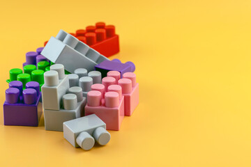 Toy colorful plastic blocks isolated on yellow background