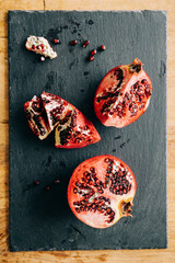 Pomegranate on a slate cut open with a knife with its seeds on display