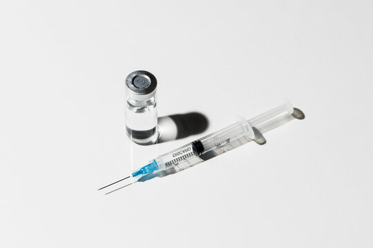 COVID-19 vaccine vial and syringe on white background
