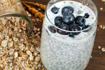 Chia pudding in a glass with blueberries and oat flakes on a wooden background. Top view. Healthy eating concept.