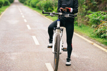 Cyclist use smartphone when riding mountain bike on forest trail