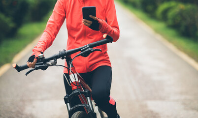 Cyclist use smartphone when riding mountain bike on forest trail
