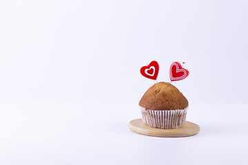Homemade muffin with heart shape candles on white background. Holiday and Valentin day gift card background with copy space.
