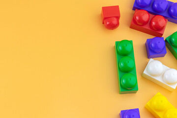 construction toy plastic figures and bricks on a yellow background. Colorful plastic bricks.