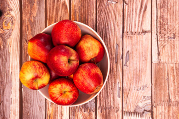 Red apples inside a bowl on a wooden table