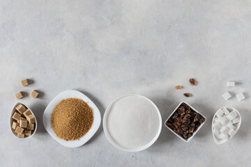 Different white and brown sugar in assortment top view on grey background.