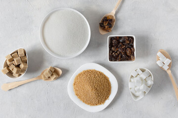 Different white and brown sugar in assortment top view on grey background.