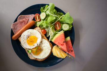 Breakfast with fried eggs, sausage, bacon and mix vegetables