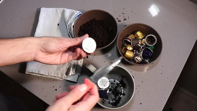 Hombre  cauc&aacute;sico vaciando c&aacute;psulas de caf&eacute; para llavarlas a reciclar 