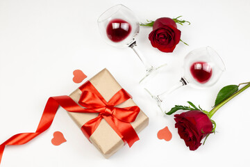 Fototapeta na wymiar Red roses and wine glasses with red wine on white background. Holidays and Valentin’s day romantic flat lay, top view concept