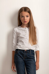 girl child with long hair in a white blouse and jeans on a white background